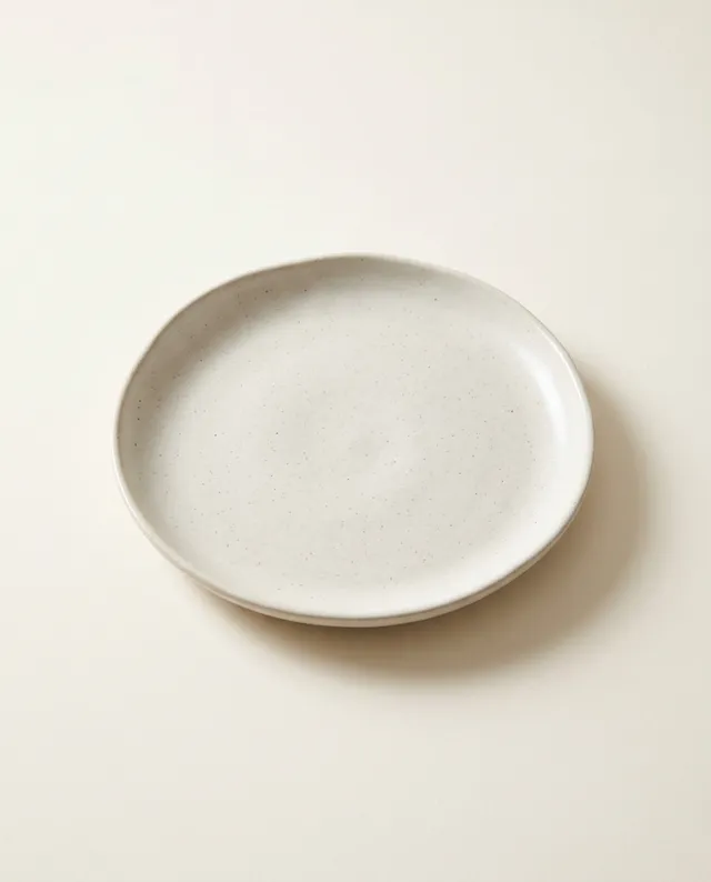 Une assiette creuse à l'émail blanc cassé, au bord légèrement relevé.